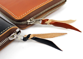 ラウンドジップ二つ折り財布（牛革）、ファスナーには本体と同じ革で飾り紐がついており、開閉がしやすくなっています。